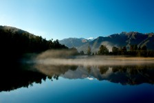 Sun catches early morning mist at Lake Matheson